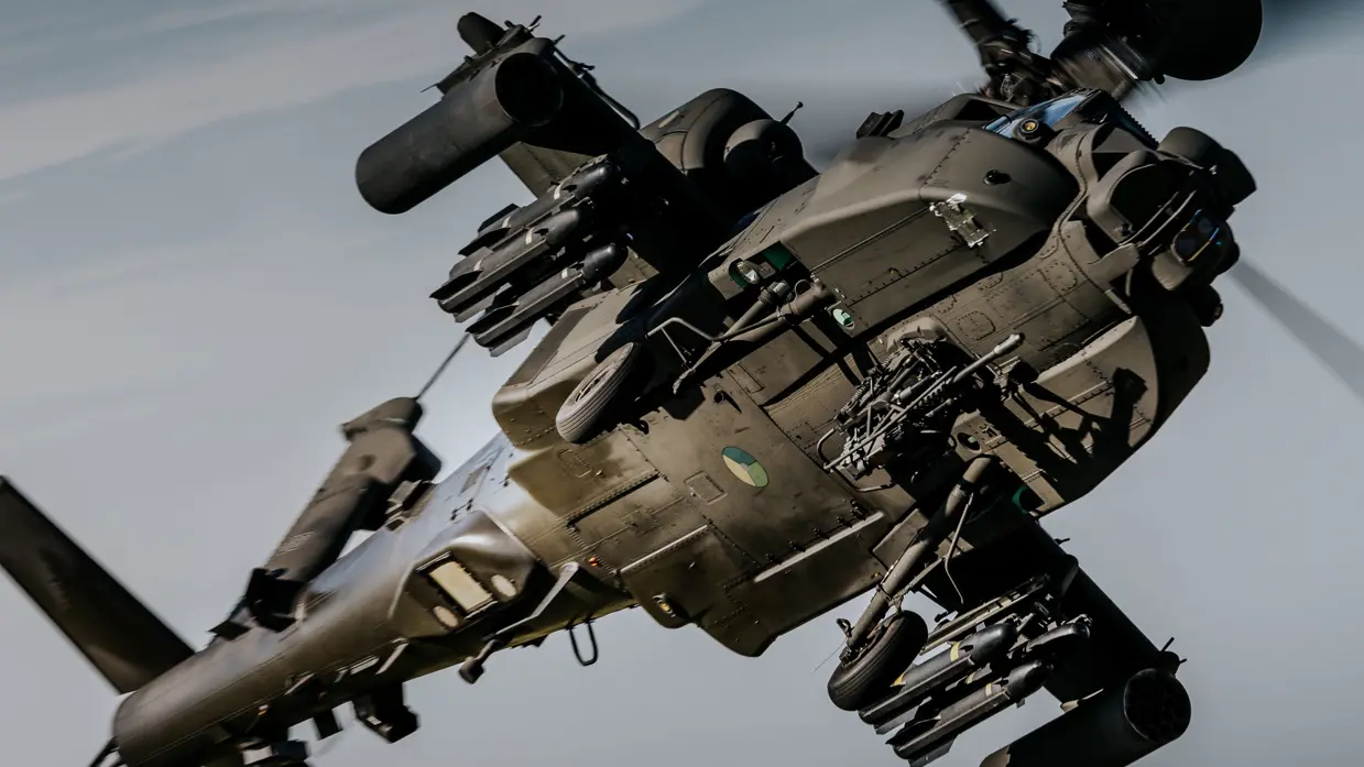 De onderkant van een vliegende Apache-helikopter is zichtbaar.