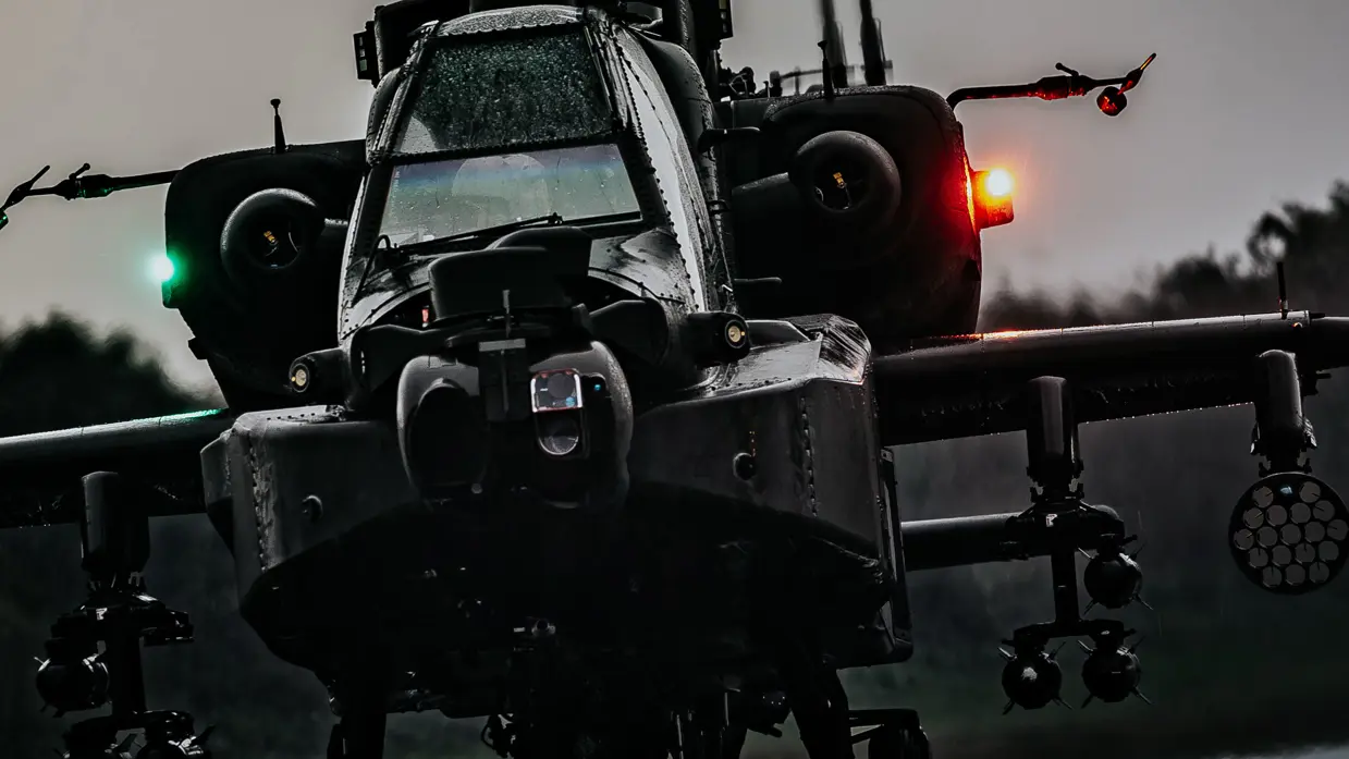 De voorkant van een optrekkende Apache-helikopter in schemerlicht.