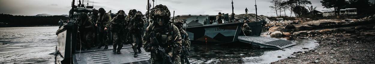 Mariniers stappen op strand uit amfibische vaartuigen.