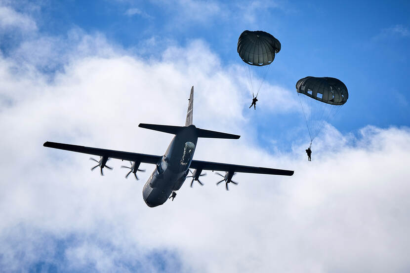 Een transportvliegtuig dropt parachutisten.