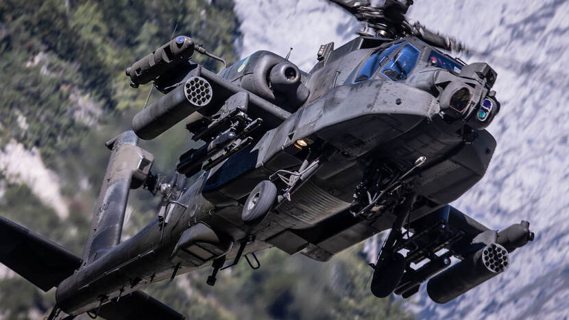 Een Apache-gevechtshelikopter vliegt in bergachtig gebied.