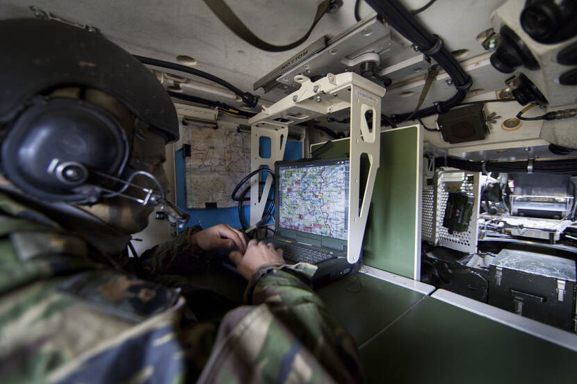 Een militair die op een laptop aan het werk is.
