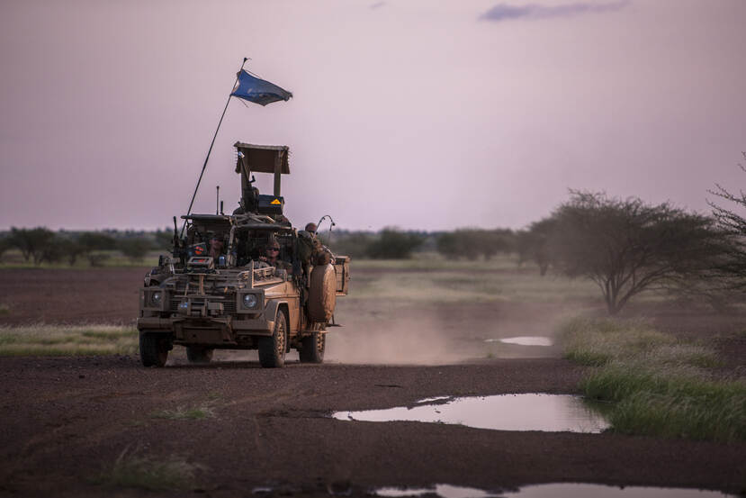 Een militair voertuig rijdt door een stoffig landschap.
