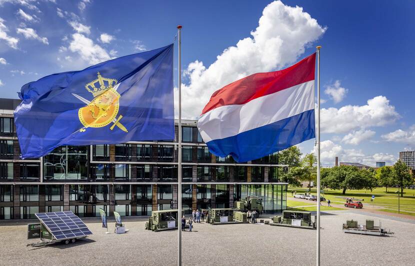 3 generatoren van Defensie gepresenteerd op een kazerneterrein in Utrecht met wapperende vlaggen op de voorgrond.