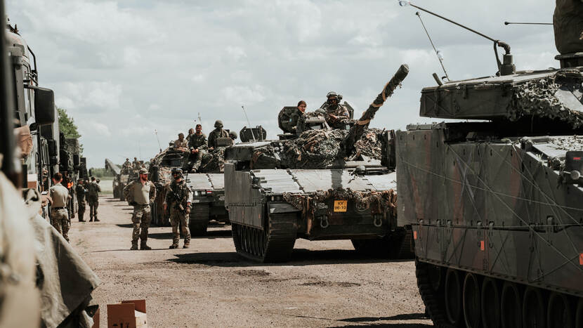 Militairen en hun voertuigen staan op een weg.