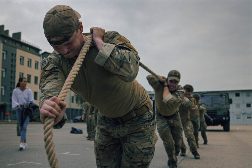 Militairen trekken met een touw een militair voertuig.
