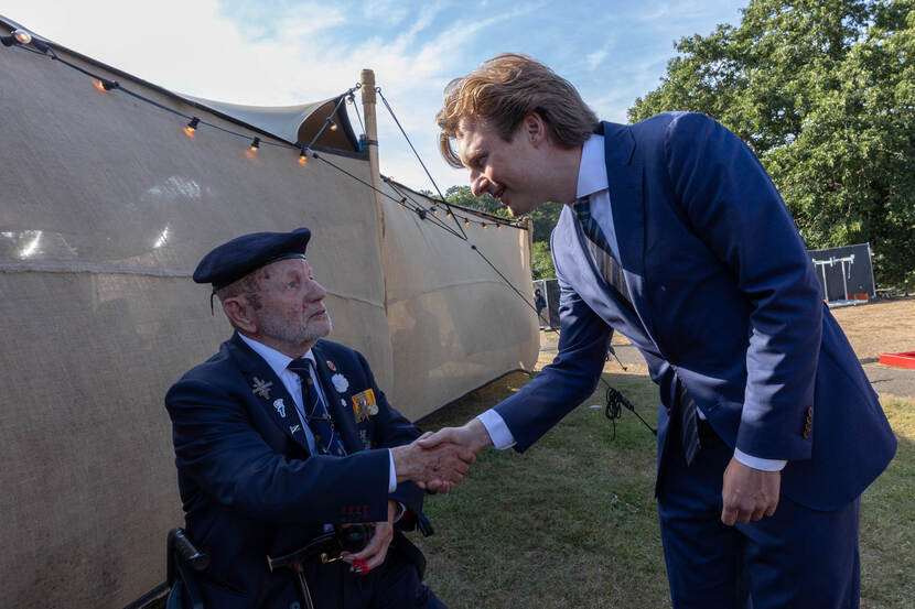 Minister geeft hand aan een veteraan.