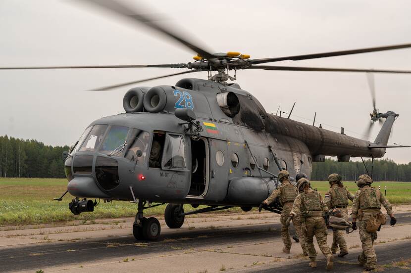 Militairen rennen met gewonde op brancard naar draaiende heli.