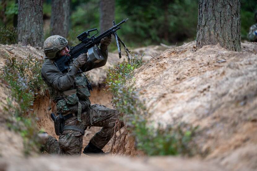 Militair in kuil met wapen omhoog gericht.