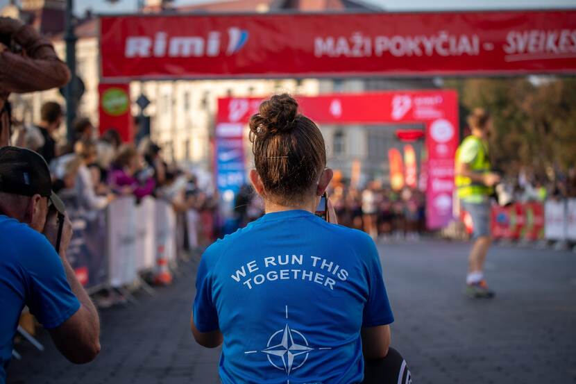 Vrouw in blauw T-shirt op de rug gezien. Tekst op shirt 'we run this together'