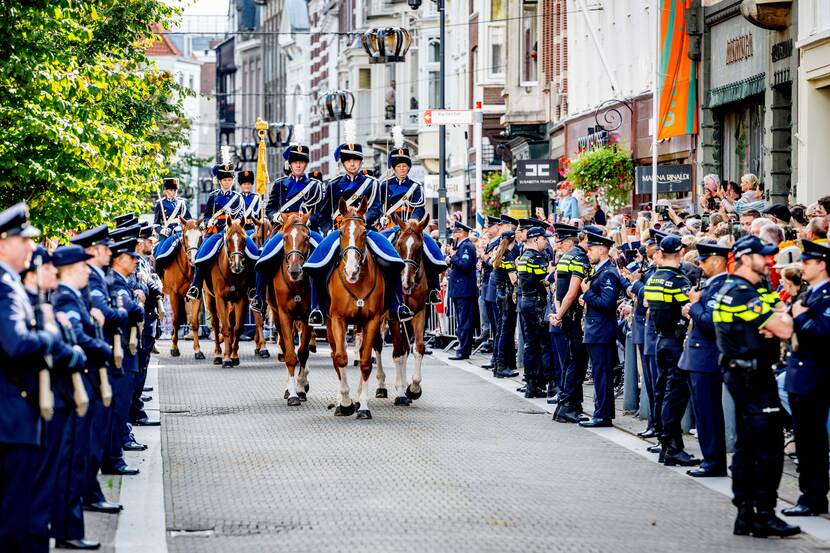 Marechaussee te paard komt hoek om met aan weerskanten opgestelde militairen.