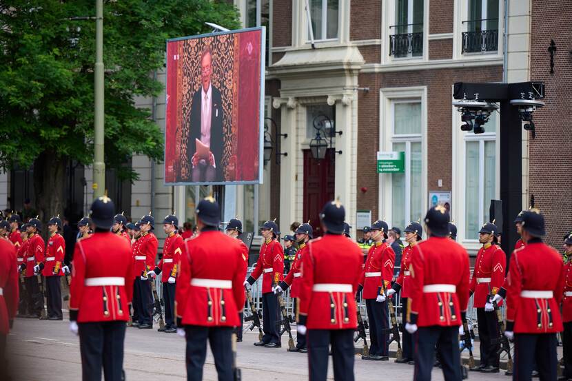 Opgestelde militairen in rood ceremonieel tenue.