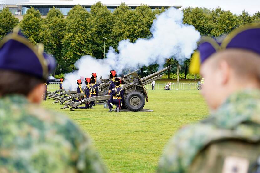 Kanonnen worden afgevuurd. Militairen in ceremonieel tenue.