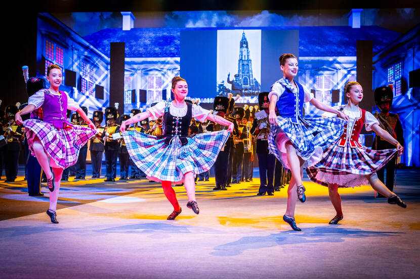 De Koninklijke Militaire Kapel Johan Willem Friso met op de voorgrond vier danseressen van The International Tattoo Highland Dance Team.