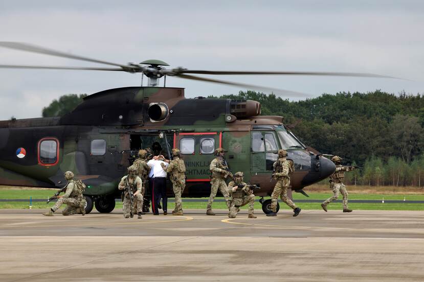 Helikopter op de grond met militairen in actie eromheen.