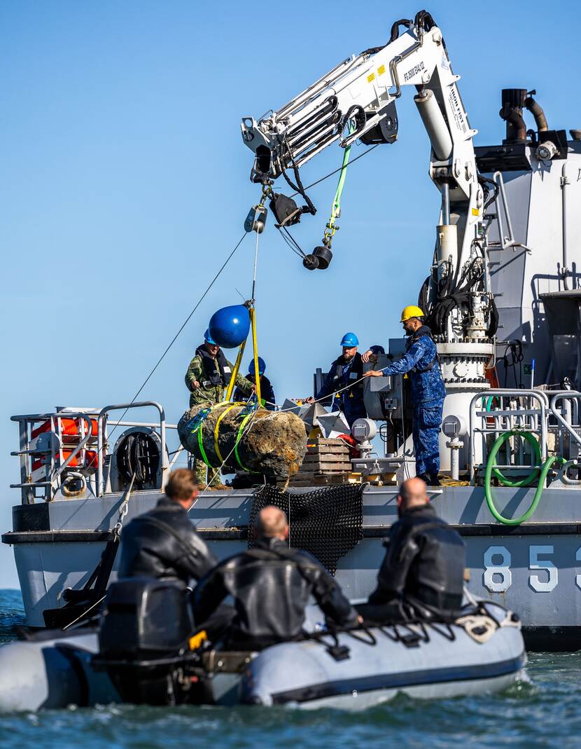 Militairen takelen zeemijn van schip.