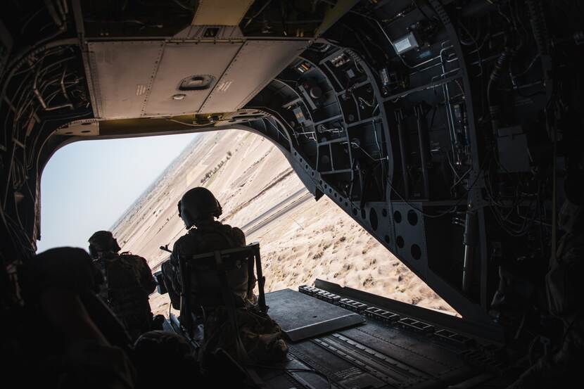 Militairen bij open deur Chinook-helikopter.