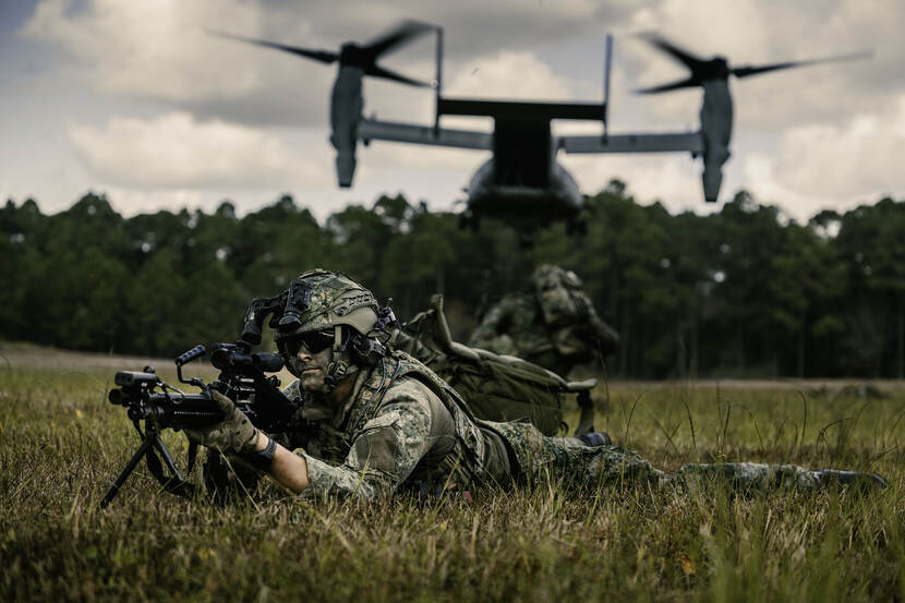 Militair ligt op de grond met een vliegtuig boven zijn hoofd.