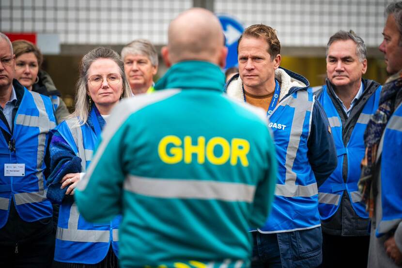 Staatssecretaris Gijs Tuinman luistert naar een man in een jas waar 'GHOR' op staat.