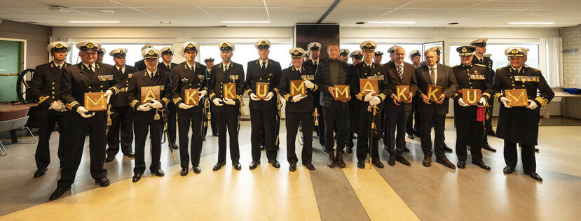 Militairen van de marine poseren met letters van naamborden.