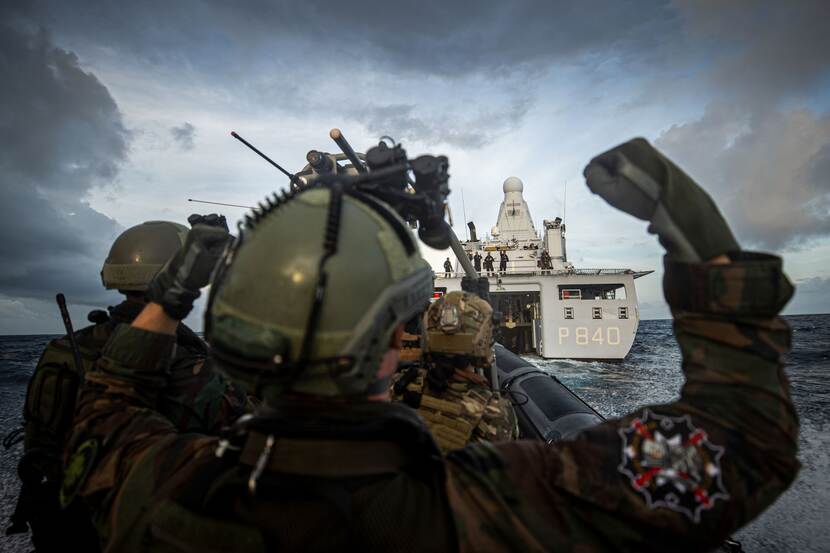 Militairen op rug gezien varen in onderscheppingsboot naar Zr.Ms. Holland.