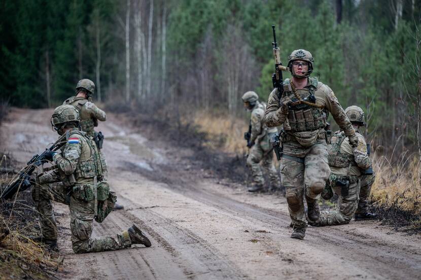 Militairen in actie in op zandpad in bos.