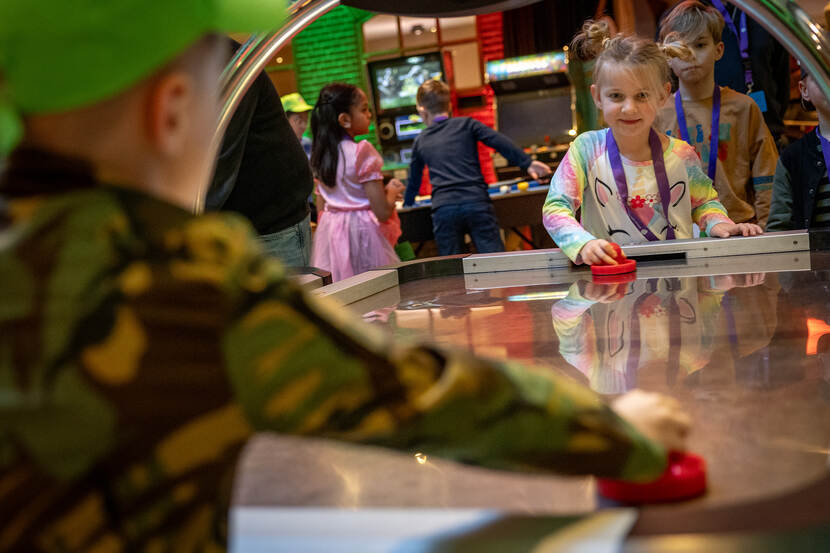 Twee kinderen spelen aan een tafel tijdens het evenement in Nijkerk. De jongen draagt een jasje met legervlekken.