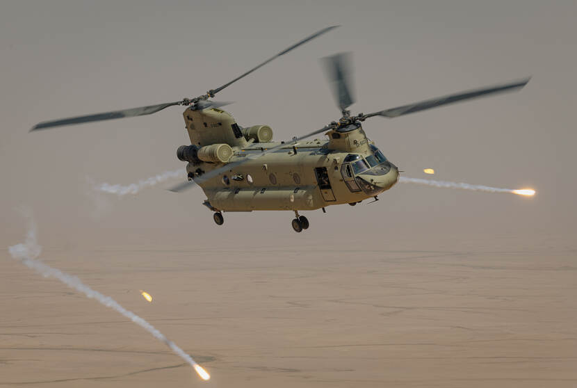 Een Chinook transporthelikopter boven land.