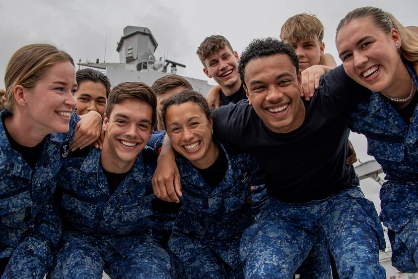 Een groep lachende jongeren in gevechtskleding van de marine.