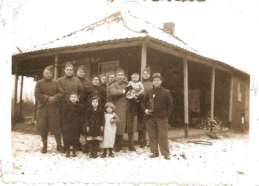 Historische groepsfoto militairen met kinderen.