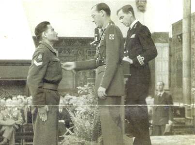 Zwart-wit foto van militair die medaille krijgt van Prins Bernhard.