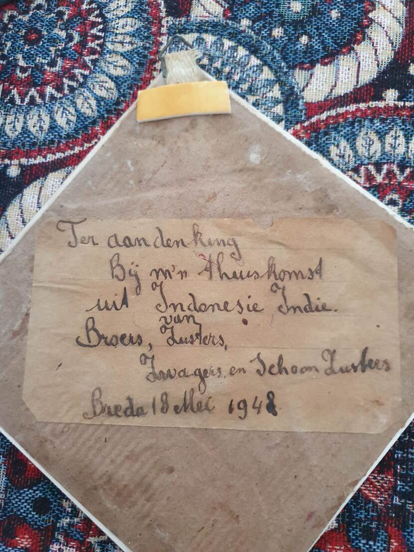 Kaart op de achterkant van een tegeltje met de tekst: ter aandenking bij mijn thuiskomst uit Indonesië, Indië. Van broers, zuster, zwagers en schoonzusters. Breda 18 mei 1948.