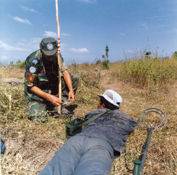 Militair geeft in het veld instructie over mijnen ruimen.