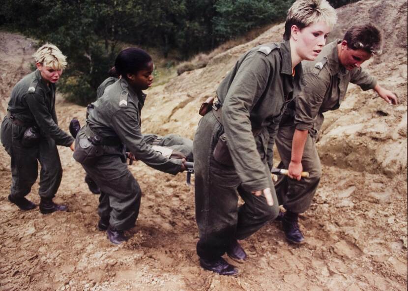 Vrouwelijke korporaals sjouwen oefengewonde op brancard (ca. 1990).