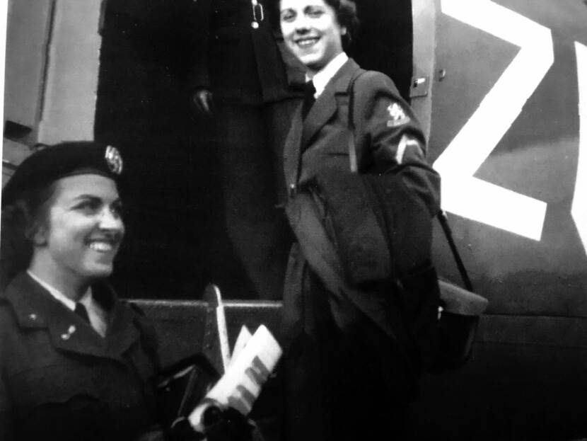 Twee militairen van het Vrouwen Hulpkorps stappen in het vliegtuig