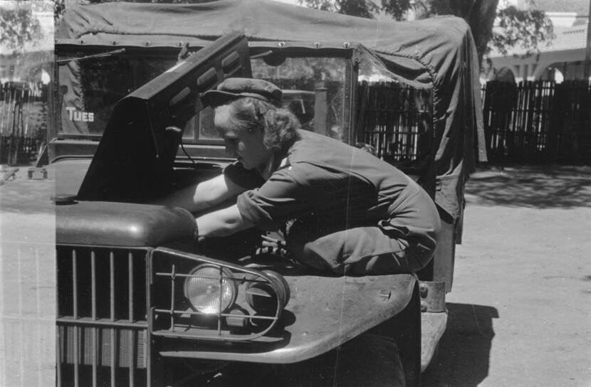 De vrouwelijke chauffeur Willinck kijkt in de motor van een voertuig.
